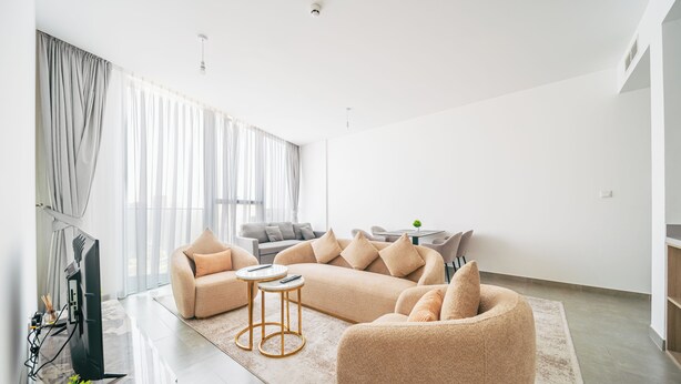 A modern living room with a sectional sofa, a round coffee table, and a flat-screen TV. - Cozy 1 Bedroom In High Floor In Dubai Marina (Dubai)
