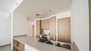 A modern kitchen with wooden cabinets, a stainless steel sink, and a built-in oven. - Cozy 1 Bedroom In High Floor In Dubai Marina (Dubai)