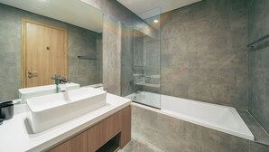 A modern bathroom with a wooden door, a white sink, a glass shower enclosure, and a white bathtub. - Cozy 1 Bedroom In High Floor In Dubai Marina (Dubai)