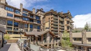 Un hotel de varios pisos con fachada de piedra y madera, balcones y un espacio al aire libre cubierto.