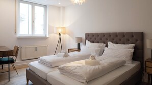 A double bed with white linens, a tufted headboard, and two bedside tables with lamps. - ღLiboria | Elegance at Josephsplatz (München)