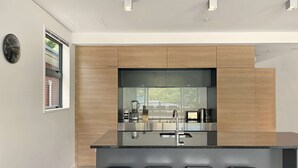A modern kitchen with a central island, bar stools, and a large window.