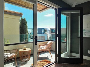 A balcony with wicker chairs, a small round table, and a glass door leading to an outdoor area.