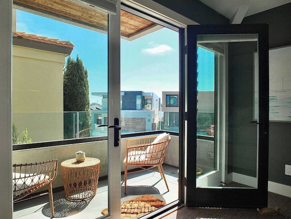 A balcony with wicker chairs, a small round table, and a glass door leading to an outdoor area.