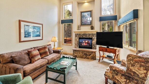 A cozy living room with a fireplace, comfortable seating, and large windows.