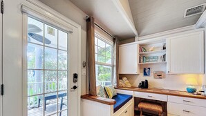 A room with a bay window, a built-in bench, a small desk, and a cabinet with shelves.