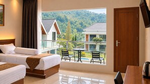 A hotel room with a balcony, two beds, a dining table, and a TV. - Grand Wijaya Hotel dan Villa Sarangan (Plaosan)