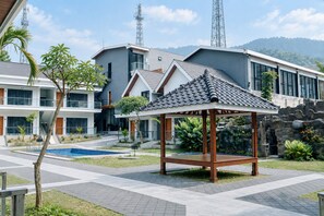 A modern hotel with a pool, a gazebo, and a view of the surrounding landscape. - Grand Wijaya Hotel dan Villa Sarangan (Plaosan)