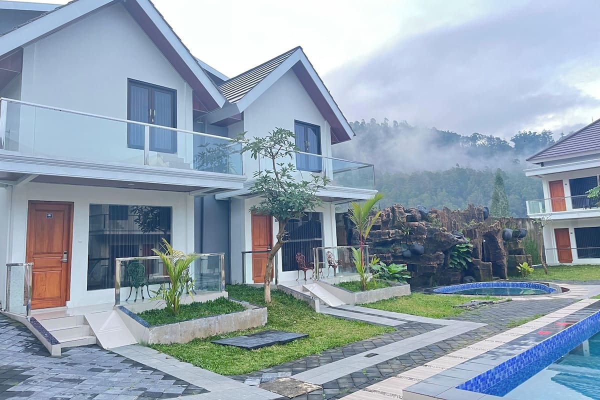 Uma casa moderna de dois andares com varanda, um pequeno jardim e piscina.