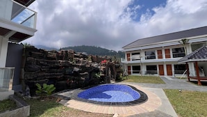 Une maison moderne avec un mur en pierre, une piscine et une vue sur les montagnes.