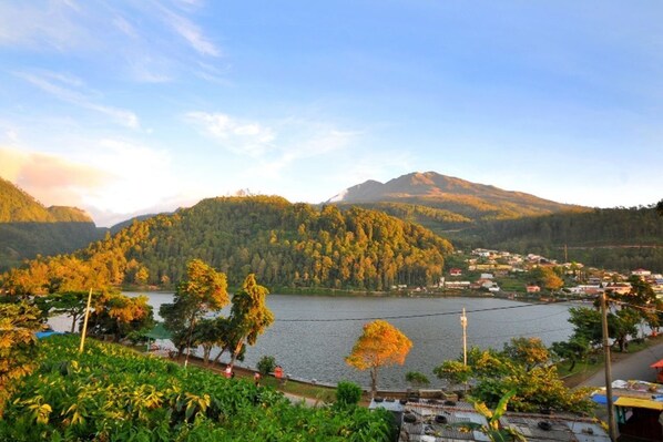 Vista panorámica de un lago rodeado de colinas y un pequeño pueblo.