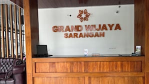 Un comptoir d’accueil avec une enseigne indiquant : « Grand Wijaya Sarangan ».