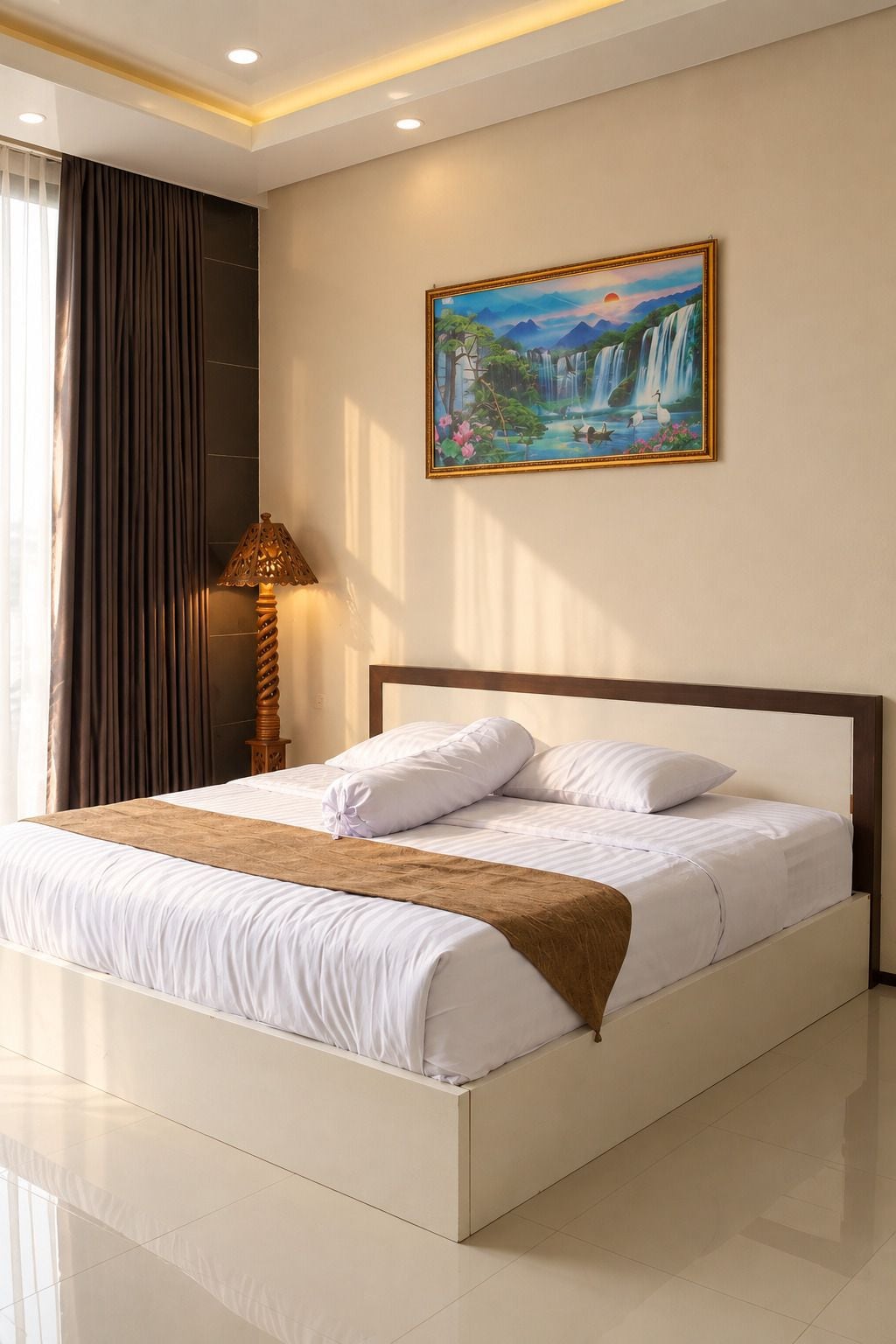 Ein Hotelzimmer mit einem großen Bett, einem Gemälde eines Wasserfalls und einer Lampe.
