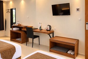 A hotel room with a bed, a desk with a chair, a television, and a shoe storage unit. - Grand Wijaya Hotel dan Villa Sarangan (Plaosan)