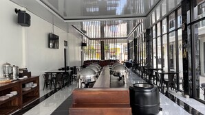 Un restaurant moderne doté d’un long comptoir, de présentoirs en métal et offrant une vue dégagée grâce à de grandes fenêtres.