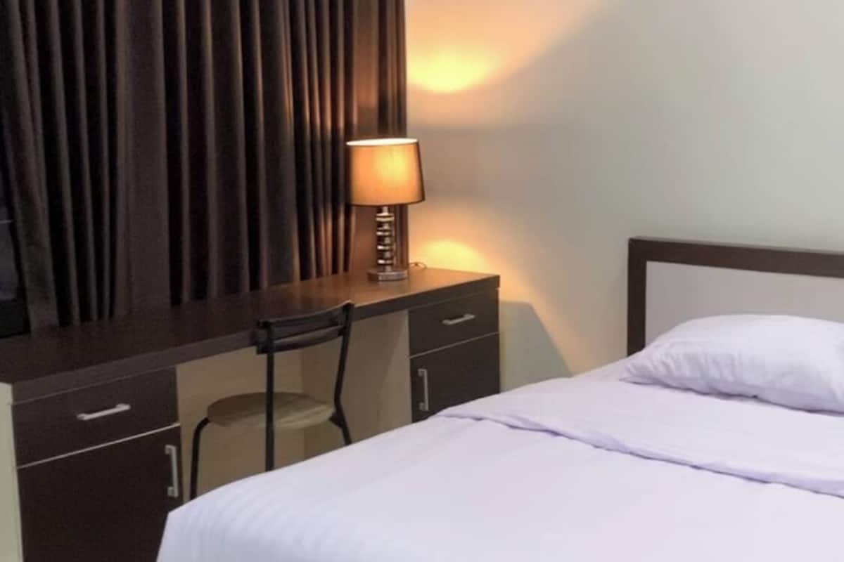 Um quarto com uma cama, uma escrivaninha e uma cadeira.