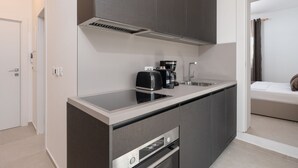 Eine kompakte Küche mit eingebautem Herd, einer Kaffeemaschine und einer Mikrowelle.