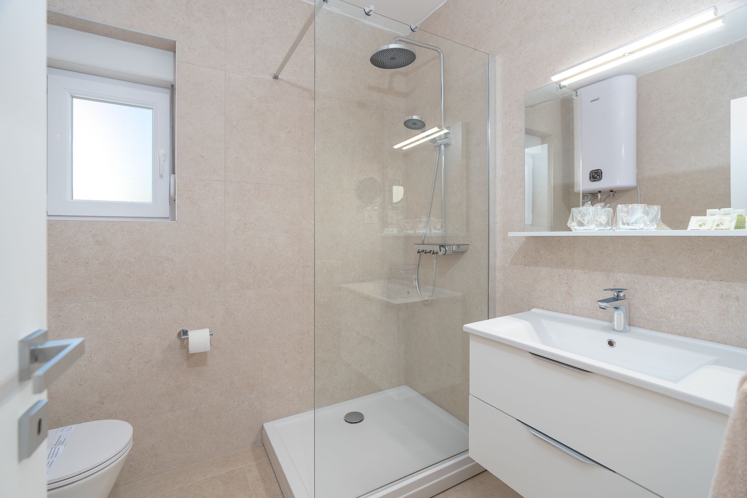 Een moderne badkamer met een douchecabine van glas, een wit wastafelmeubel en een toilet.