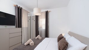Ein modernes Hotelzimmer mit einem großen Bett, einem Flachbildfernseher, einem Schminktisch und einem Spiegel.