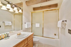 A bathroom with a bathtub, toilet, and sink. There are towels hanging on the wall and a mirror above the sink.