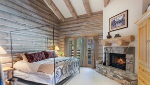 Camera da letto in stile baita con un letto a baldacchino, un camino in pietra e un soffitto in legno.