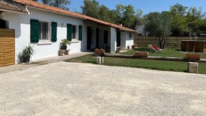 A white building with a red-tiled roof, green shutters, and a gravel driveway. - Le Grand mazet (ARLES)