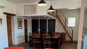 A spacious living area with a dining table and chairs, a staircase, and a kitchen area. - Le Grand mazet (ARLES)