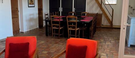Amplia sala de estar con mesa y sillas de comedor, una escalera y una zona de cocina.