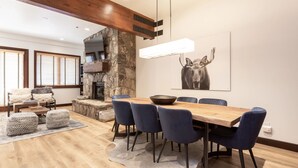 A modern dining area with a wooden table, blue chairs, and a stone fireplace. - Trail's End Lodge at Deer Valley Resort - Two Bedroom Residence with Spa #402 2 Condo (Park City)