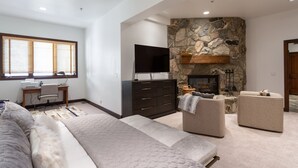 A modern living room with a stone fireplace, a flat-screen TV, a desk, and comfortable seating. - Trail's End Lodge at Deer Valley Resort - Two Bedroom Residence with Spa #402 2 Condo (Park City)