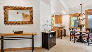 A modern kitchen with wooden cabinets, a dining area with a round table and chairs, and a large mirror with a unique frame. - Trail's End Lodge at Deer Valley Resort - One Bedroom Residence with Spa #205 1 Condo (Park City)