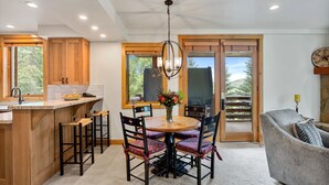 A modern kitchen with wooden cabinets, a central island, and a dining area with a round table and chairs. - Trail's End Lodge at Deer Valley Resort - One Bedroom Residence with Spa #205 1 Condo (Park City)