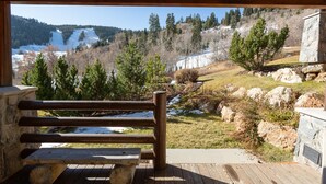 A wooden bench and stone wall overlooking a snowy landscape with trees and a clear sky. - Trail's End Lodge 4 Bedroom Condo #17 with Spa by Deer Valley Resort (Park City)