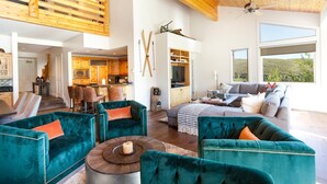 A spacious living area with teal upholstered sofas, a wooden ceiling, and large windows offering a view of the outdoors. - Trail's End Lodge at Deer Valley Resort - Three Bedroom Residence with Spa #506 3 Condo (Park City)