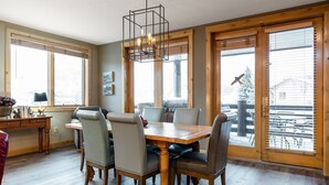 A dining area with a wooden table and chairs, large windows, and a hanging light fixture. - Trail's End Lodge at Deer Valley Resort - Two Bedroom Residence with Spa #101 2 Condo (Park City)
