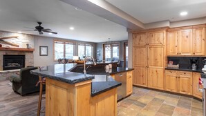 A spacious kitchen with wooden cabinets, a large island with a sink, and a stone fireplace. - Trail's End Lodge at Deer Valley Resort - Two Bedroom Residence with Spa #101 2 Condo (Park City)