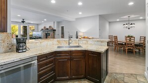 Una cucina moderna con un piano di lavoro in granito, mobili in legno e lavastoviglie integrata.