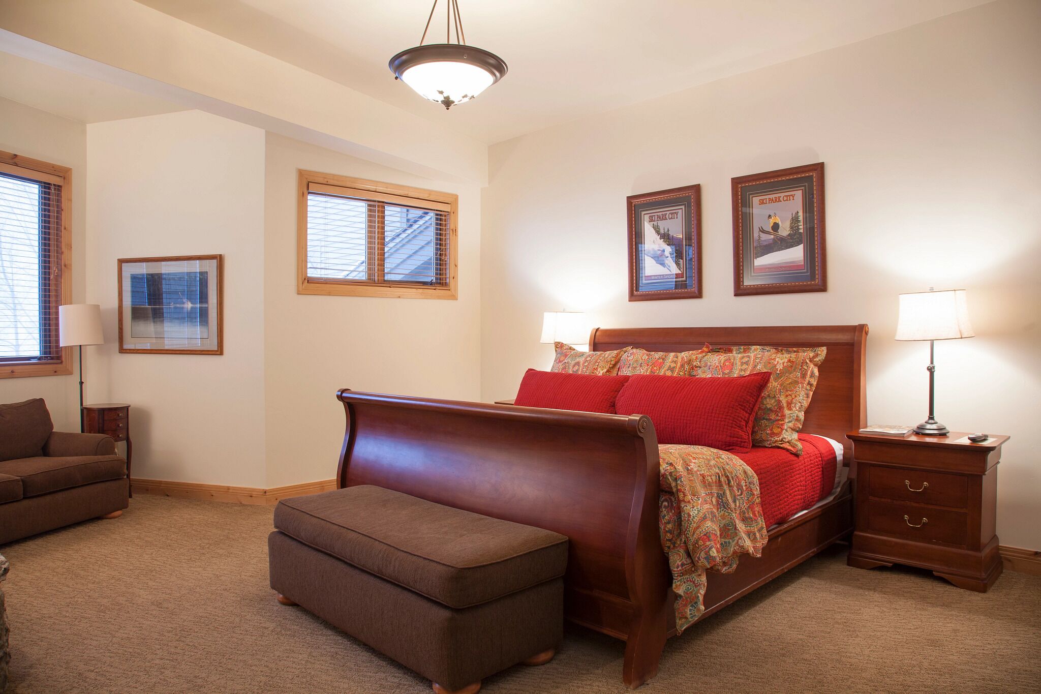 A bedroom with a wooden bed, a nightstand, a bench, and two framed pictures on the wall.