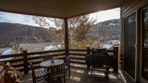 A covered deck with a table and chairs, a grill, and a view of a hilly landscape. - Trail's End Lodge at Deer Valley Resort - Two Bedroom Residence with Spa #405 2 Condo (Park City)