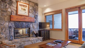 A stone fireplace with a TV, a wooden table, and a sofa in a cozy living room. - Trail's End Lodge at Deer Valley Resort - Two Bedroom Residence with Spa #405 2 Condo (Park City)