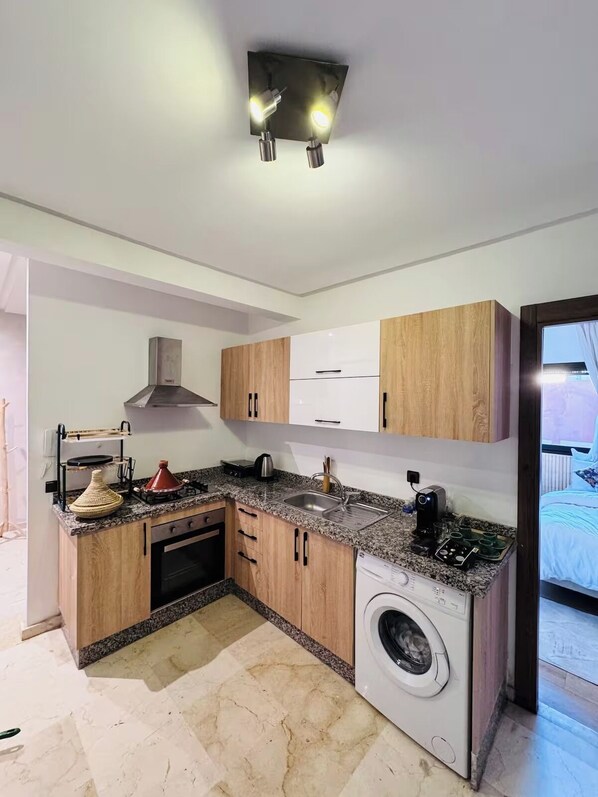 A compact kitchen with wooden cabinets, a built-in oven, a washing machine, and a sink. -  Authentic Apartment in Gueliz  Marrakesh (Marrakesh)