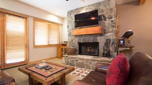 A living room with a stone fireplace, leather furniture, and a mounted TV. - Trail's End Lodge at Deer Valley Resort - Two Bedroom Residence with Spa #406 2 Condo (Park City)
