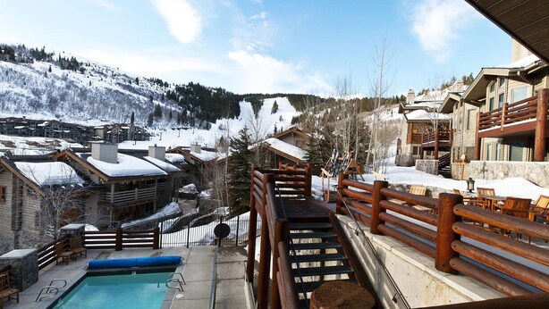 A ski resort with wooden buildings, a pool, and snowy mountains in the background. - Trail's End Lodge at Deer Valley Resort - Two Bedroom Residence with Spa #406 2 Condo (Park City)