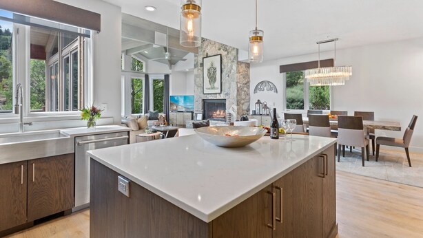 A modern kitchen with a large island, pendant lighting, and a view of the outdoors.