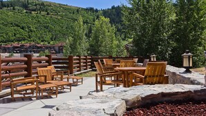An outdoor seating area with wooden furniture and a stone wall, overlooking a mountainous landscape. - Trail's End Lodge at Deer Valley Resort - One Bedroom Deluxe Residence with Spa #304 1 Condo (Park City)