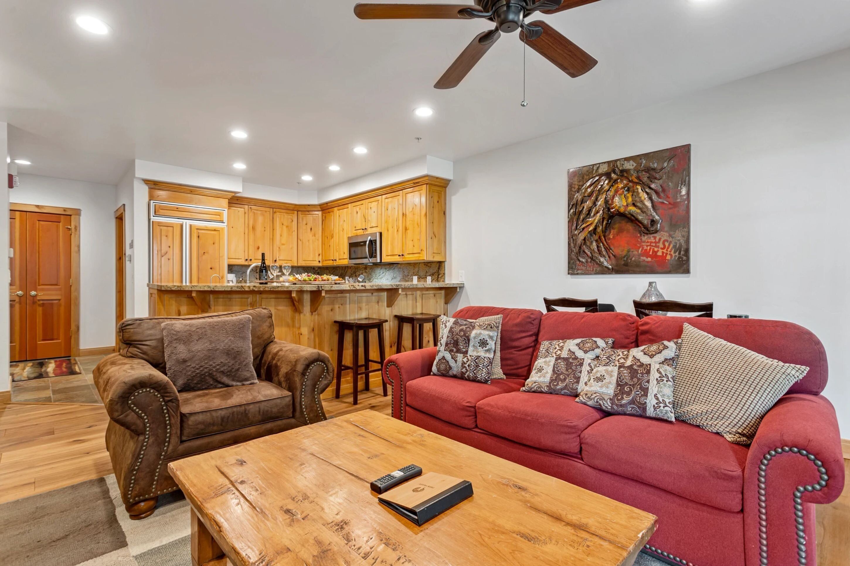 A modern living room with a red sofa, a wooden coffee table, and a ceiling fan.