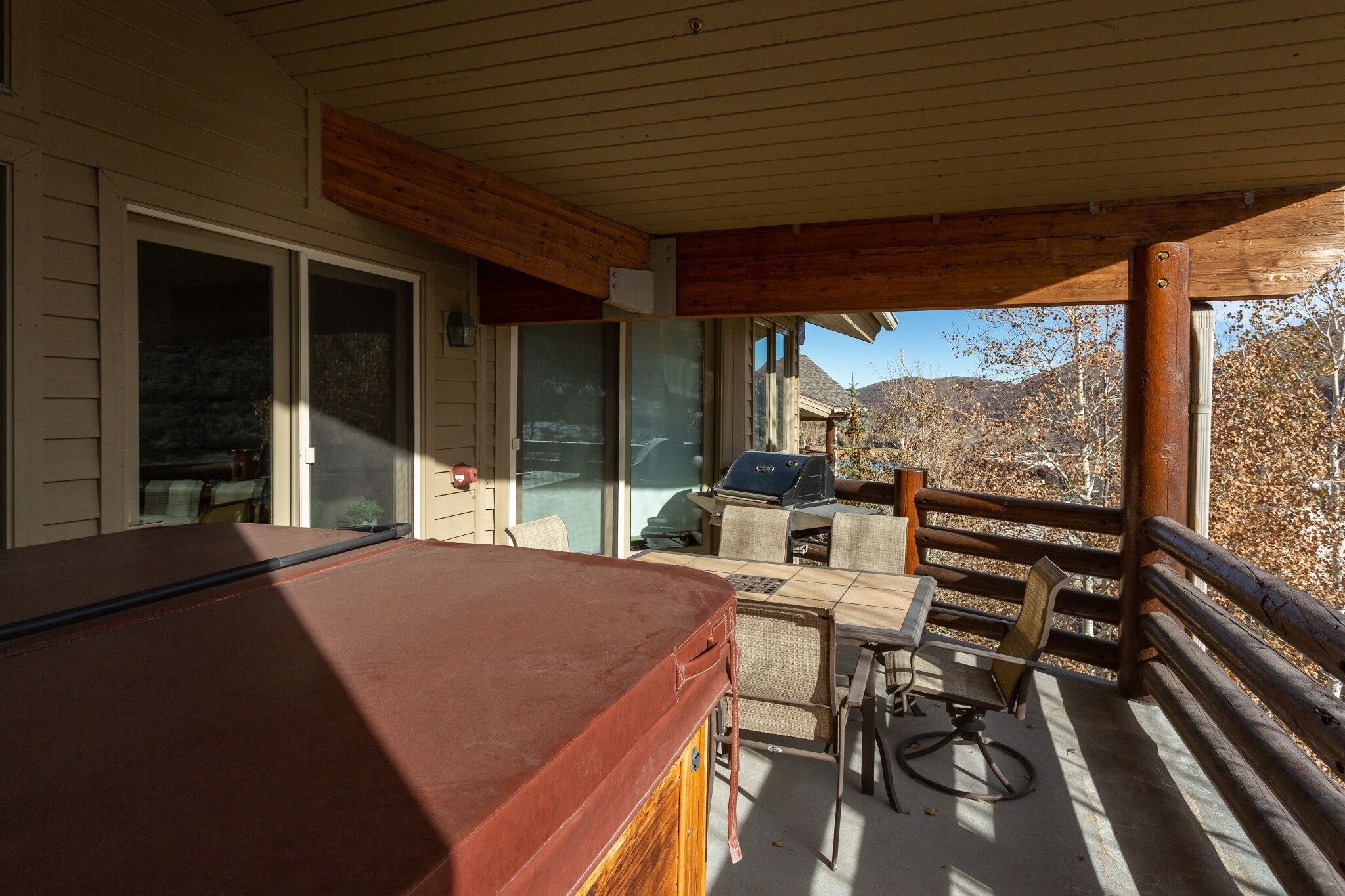 Una terraza techada al aire libre con mesa de billar, parrilla y zona de comedor con sillas y mesa.