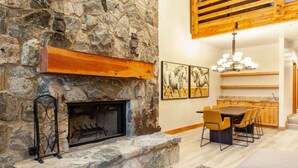 A stone fireplace with a mantel, a dining area with a wooden table and chairs, and a kitchen with wooden cabinets and a hanging light fixture. - Trail's End Lodge at Deer Valley Resort - Four Bedroom Residence with Space #504 4 Condo (Park City)