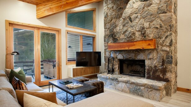 A cozy living room with a stone fireplace, a large flat-screen TV, and a comfortable seating area. - Trail's End Lodge at Deer Valley Resort - Four Bedroom Residence with Space #504 4 Condo (Park City)