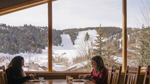 A dining area with a large window overlooking a snowy landscape with trees and a lake. - Trail's End Lodge at Deer Valley Resort - One Bedroom Residence with Spa #305 1 Condo (Park City)